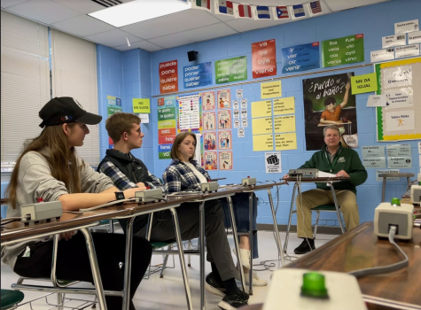 Left to right Freshman Julia Arroid, and Seniors Keegan Brown, Robot Postal getting ready to answer their questions by using buzzers to chime in.